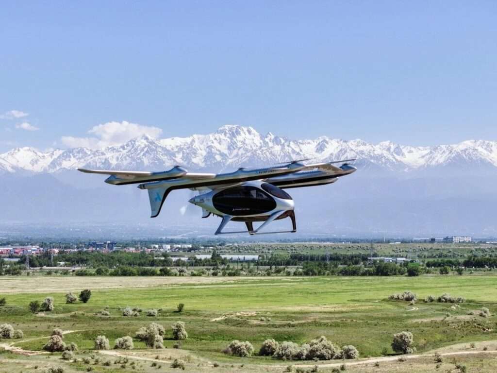 AutoFlight eVTOL aircraft in flight over a wide landscape with mountains in the background.