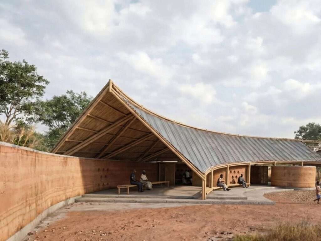Perspective under a light timber and bamboo roof next to a thick rammed earth wall with integrated seating benches.