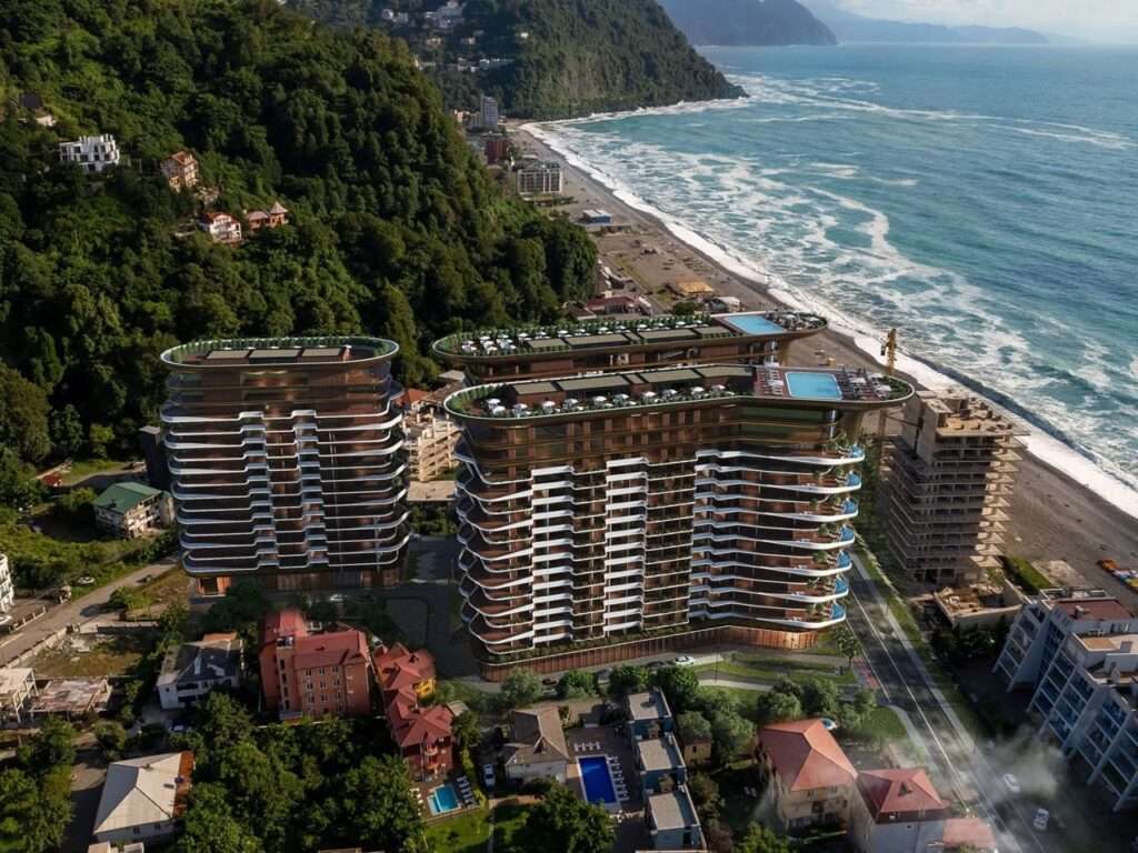 Aerial drone view of Montemar Residential development along the Gonio coastline, flanked by forested mountains and urban fabric.