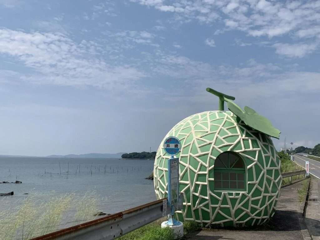 Cantaloupe melon bus stop shelter positioned next to a coastal road overlooking the ocean.