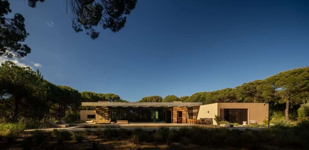 Panoramic elevation of Muda L13 residence featuring floor-to-ceiling glass wall, pool deck, and surrounding pine forest.