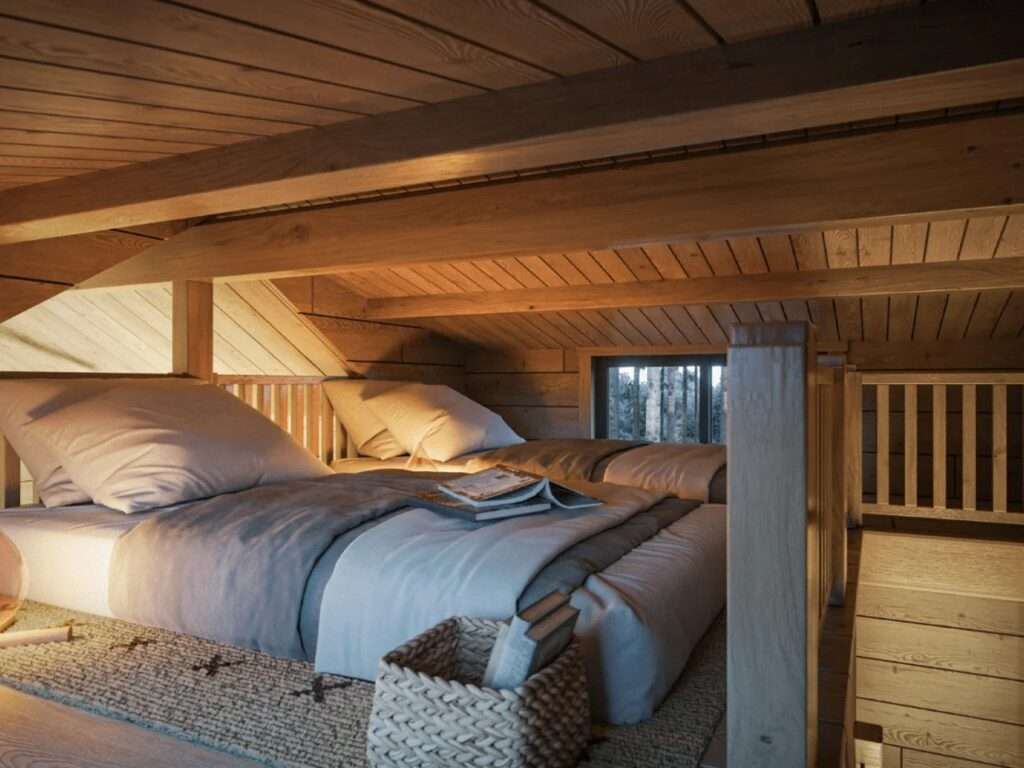 Low-ceiling sleeping loft featuring two twin mattresses on a woven rug, exposed timber roof beams, and wooden safety railings overlooking the main floor.