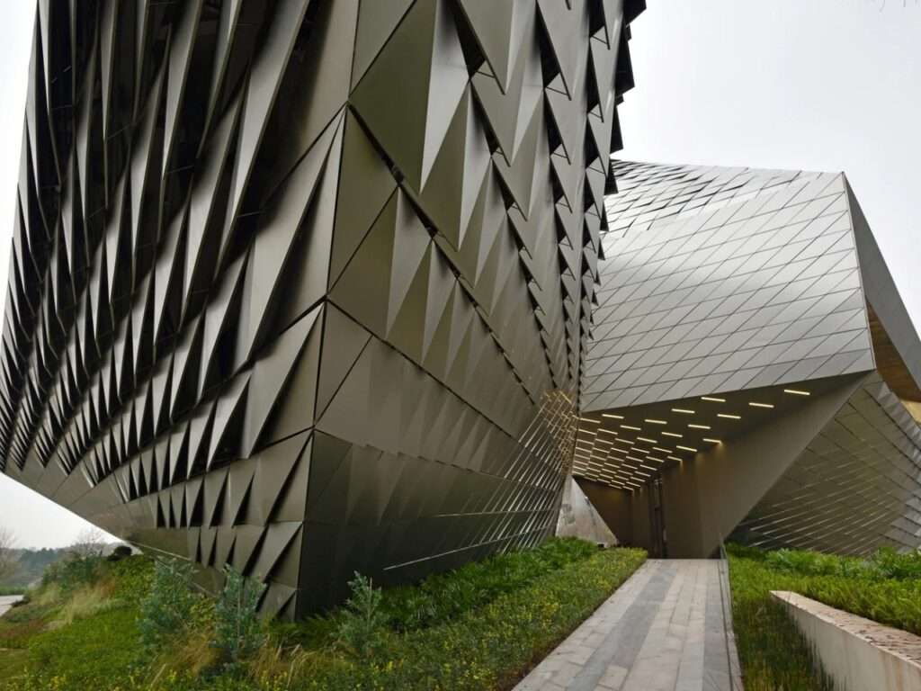 Close-up of Chengdu Pavilion's triangular perforated metal facade panels and outdoor access pathway.