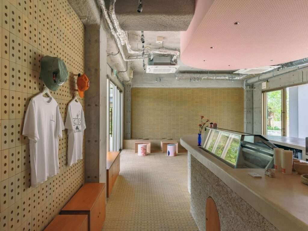 Interior corridor view showing retail display shelf with branded merchandise on perforated tile wall and service counter.