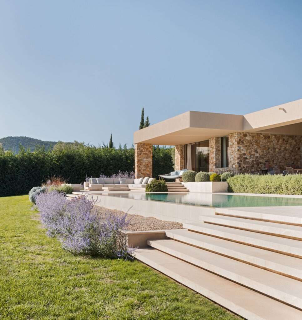 Infinity swimming pool and terraced lawn at Talleru House with wide stone steps leading up to the covered porch.