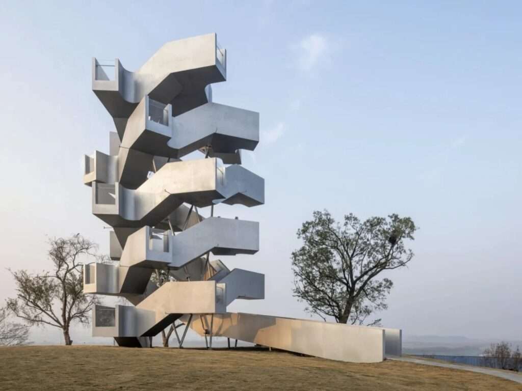 Perspective view of Qinghu Migratory Bird Observation Tower on a grassy knoll with entrance ramp under soft sunlight.