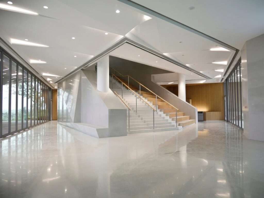 Bright public hall inside Chengdu Pavilion with a central grand staircase, marble floors, and large glass walls.