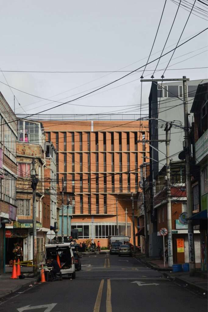 View from a narrow residential street looking towards the brick facade of Feliza Bursztyn School in Bogotá.