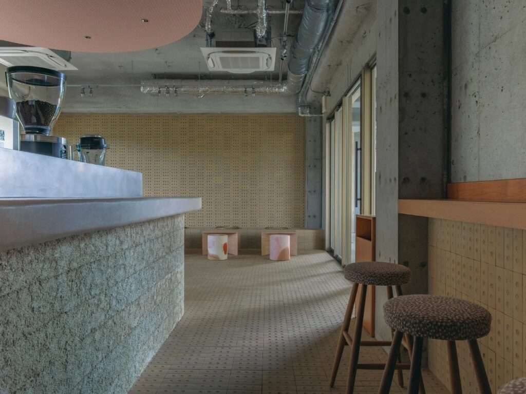 Low angle view of lime plaster counter side with wooden high bar stools along a concrete wall.