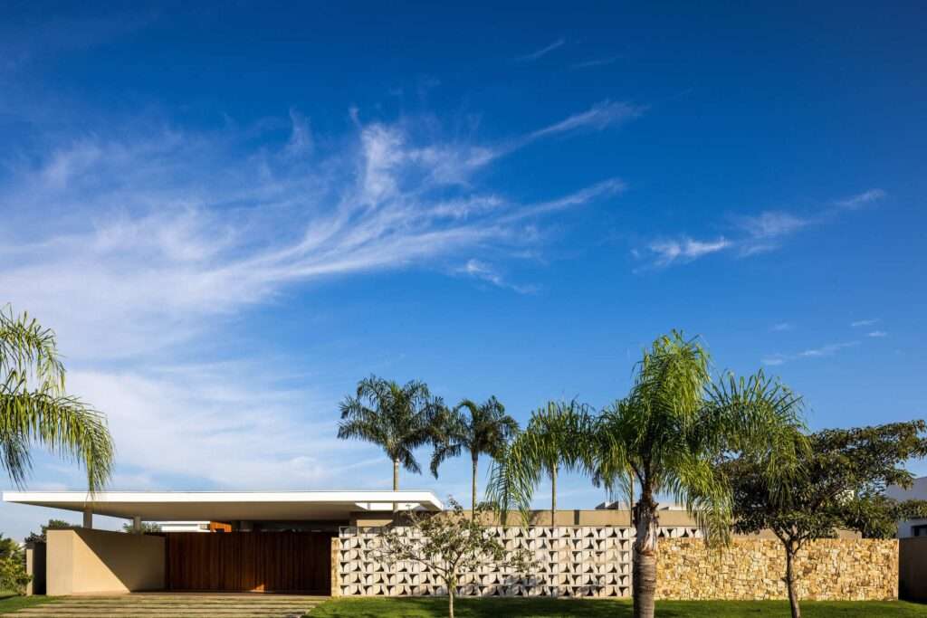 Front facade elevation of Refugio House featuring a perforated cobogo screen wall, natural stone wall, timber entrance doors, and prestressed concrete roof slab.