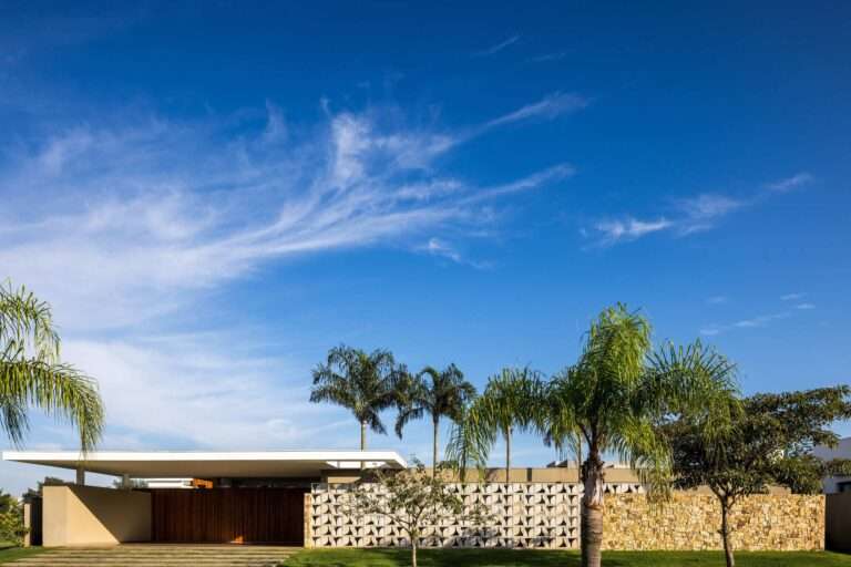 Front facade elevation of Refugio House featuring a perforated cobogo screen wall, natural stone wall, timber entrance doors, and prestressed concrete roof slab.