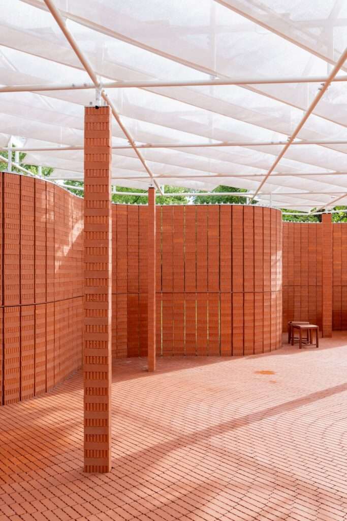 Perspective view inside the pavilion with brick pillars and dappled shadows on brick paving