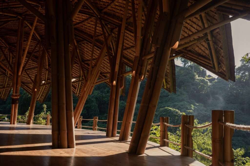 Side view of Lotus Shala's bamboo framing and wooden perimeter handrails against a lush green forest backdrop.