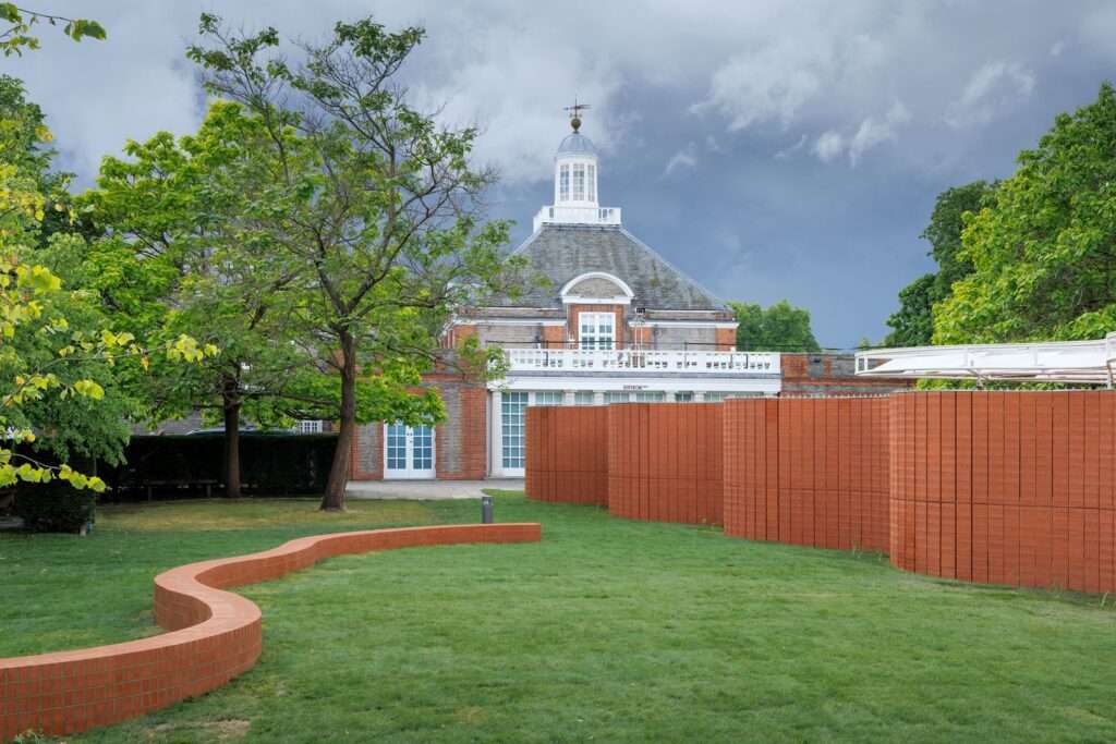 Exterior view of Serpentine Pavilion and traditional gallery building on cloudy day