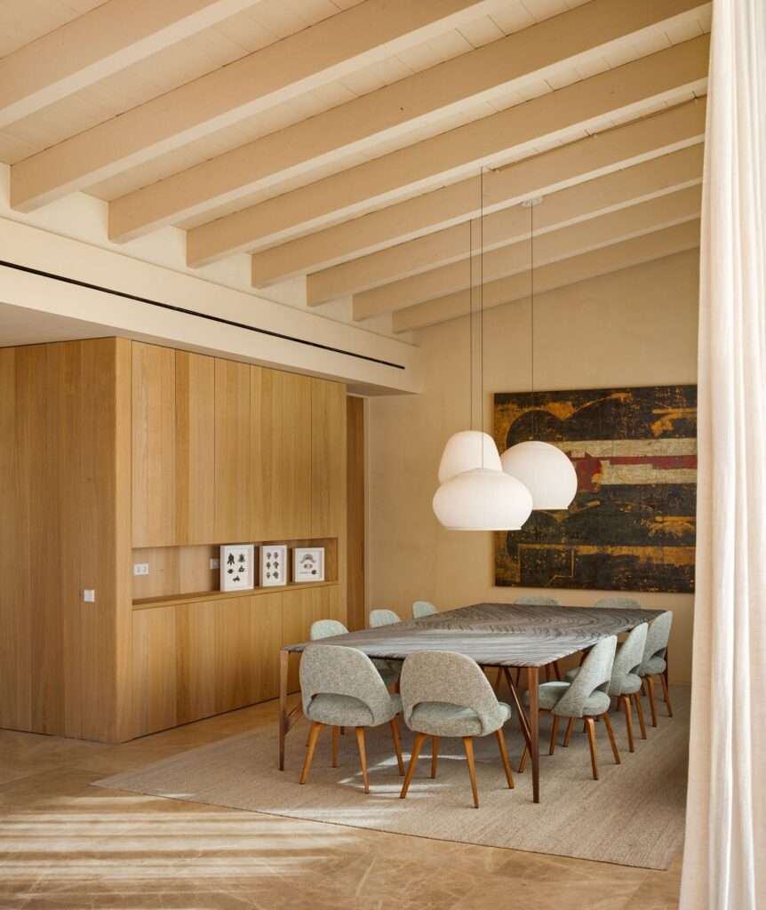 Elegant interior dining room featuring exposed wooden beam ceiling, modern pendant lights, large dining table, and oak cabinetry.
