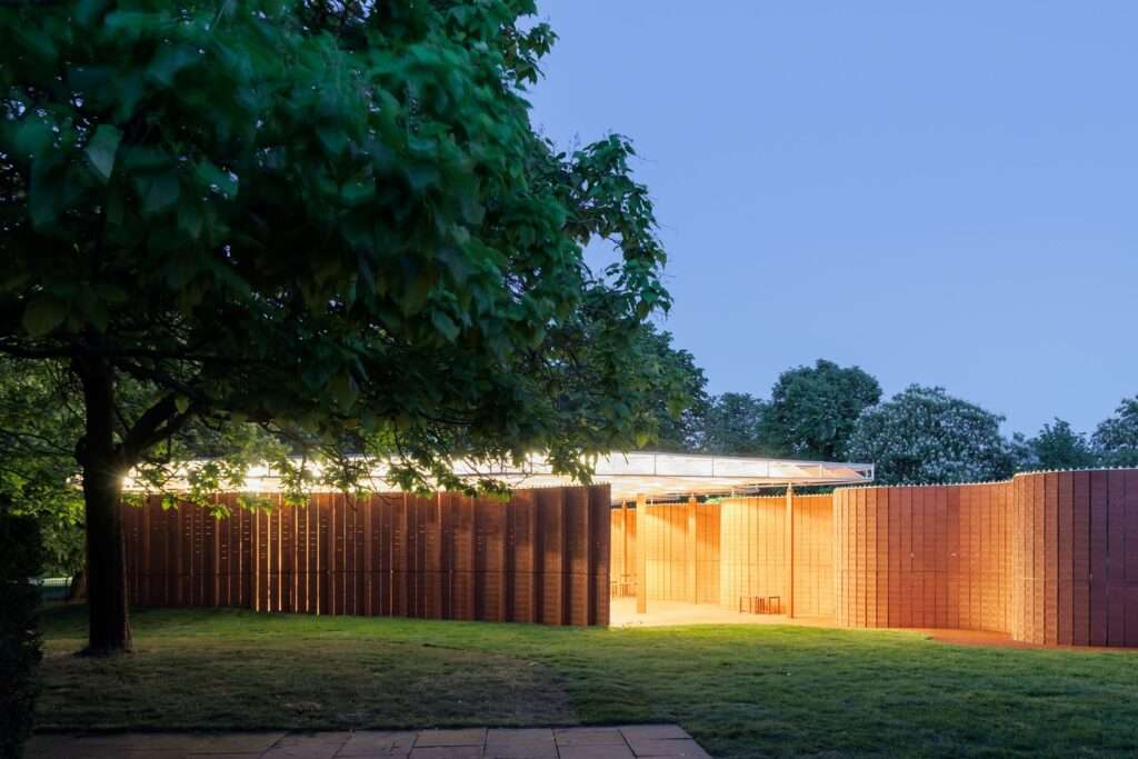 Night view of illuminated Serpentine Pavilion with glowing interior