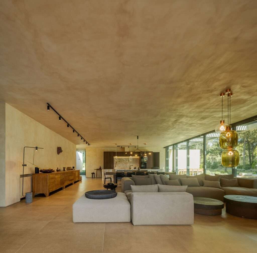 Open-plan living room interior of Muda L13 House with neutral furniture and full-height glass doors.