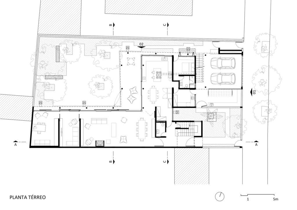 Architectural ground floor plan drawing showing L-shaped layout, central courtyard, garage, living spaces, studio, and outdoor garden.