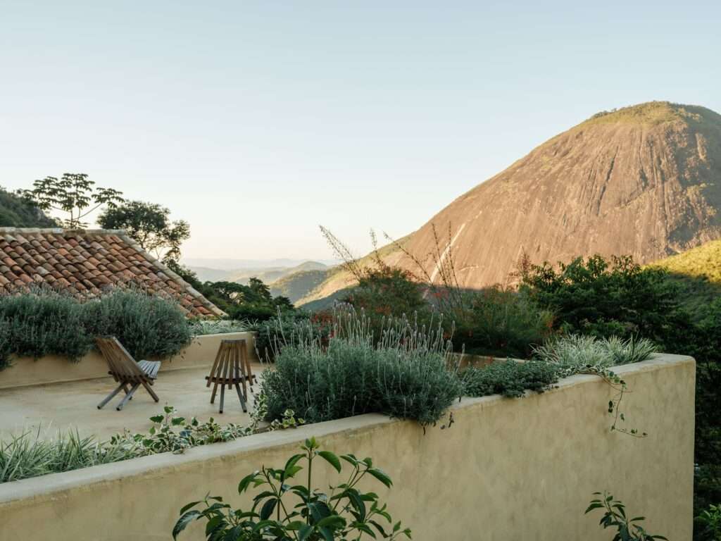 Green roof garden terrace above the private block of Japú House overlooking mountain peaks and gabled tile roof.