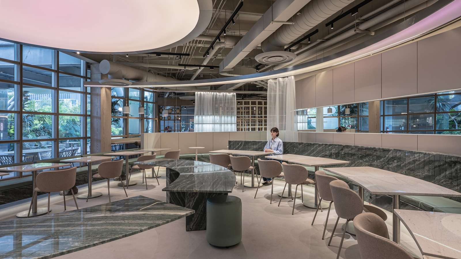 Daylight-lit dining space at Raheeq Ohm with green quartzite counters and floor-to-ceiling garden windows.