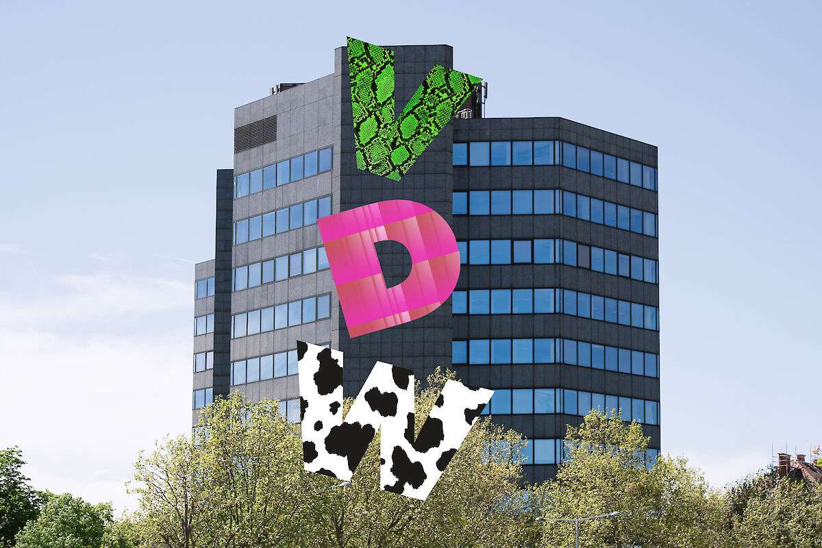 A dark gray, multi-story office building with three large, stylized letters—V, D, and W—superimposed vertically over it. The "V" has a neon green snakeskin pattern, the "D" is bright pink, and the "W" features a black-and-white cow print.