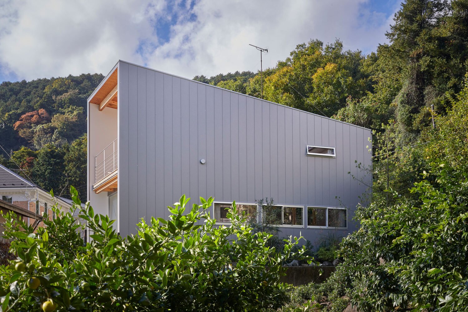 Two-story exterior facade framed by surrounding trees and lush foliage under a blue sky.