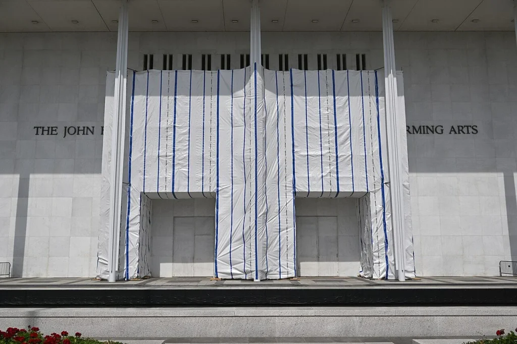 White protective tarp covering the central entrance signage section of a marble architectural elevation facade