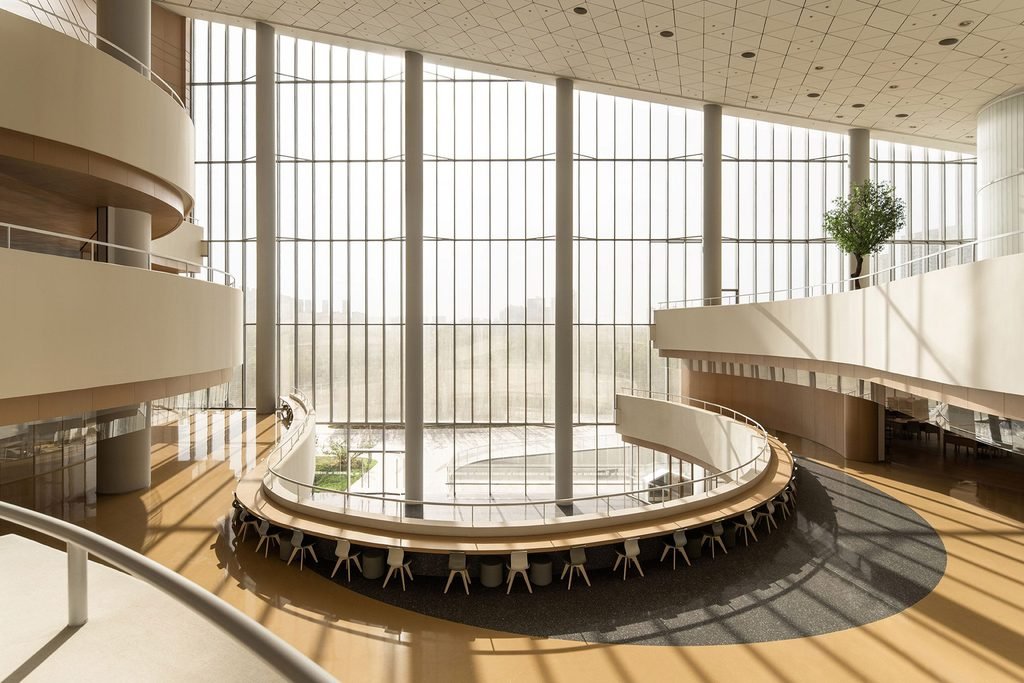 Spacious interior atrium with tall circular columns, glass curtain wall, and curved study desks.