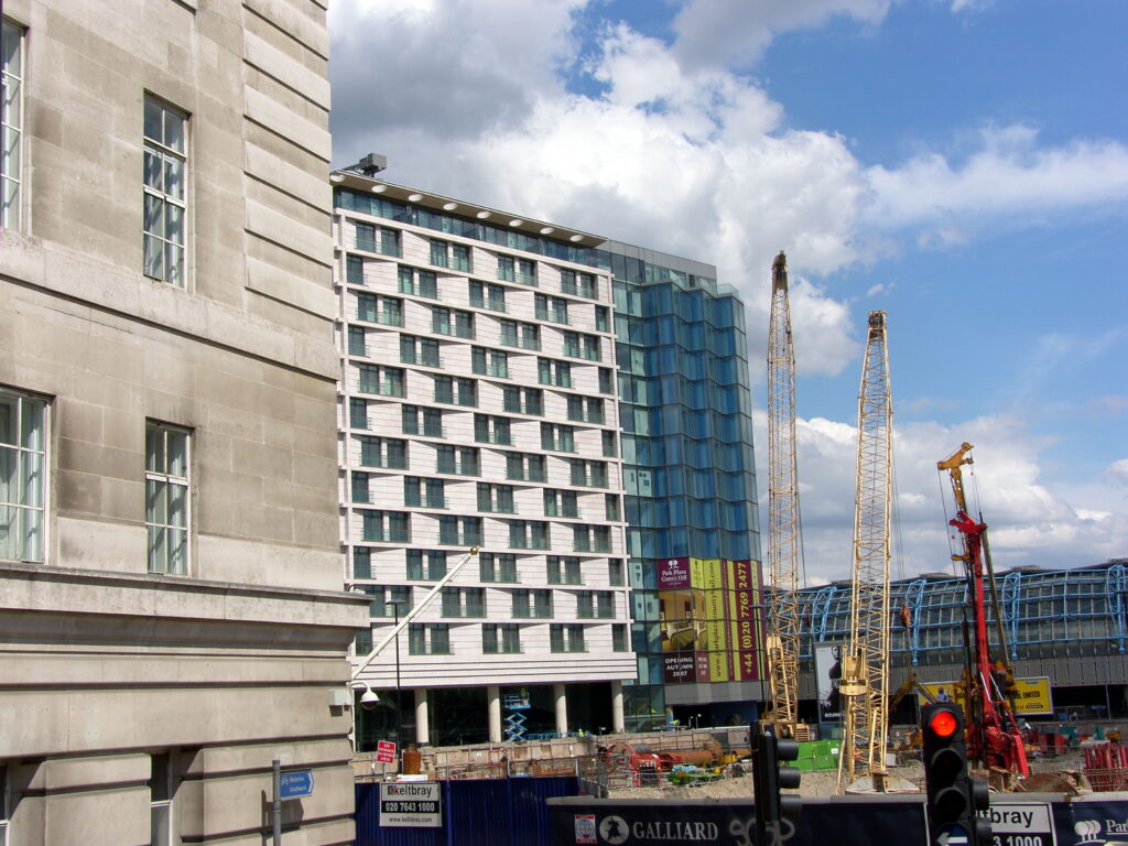 Construction site with tall yellow cranes in front of the modern Park Plaza County Hall building in London