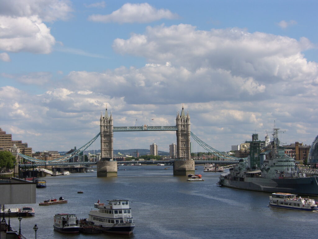 2006 Tower Bridge spanning the River Thames in London, with boats on the water and HMS Belfast docked on the right