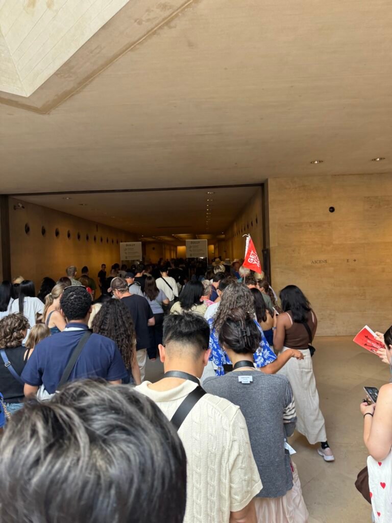 Dense visitor flow on an interior route toward the Mona Lisa at the Louvre.