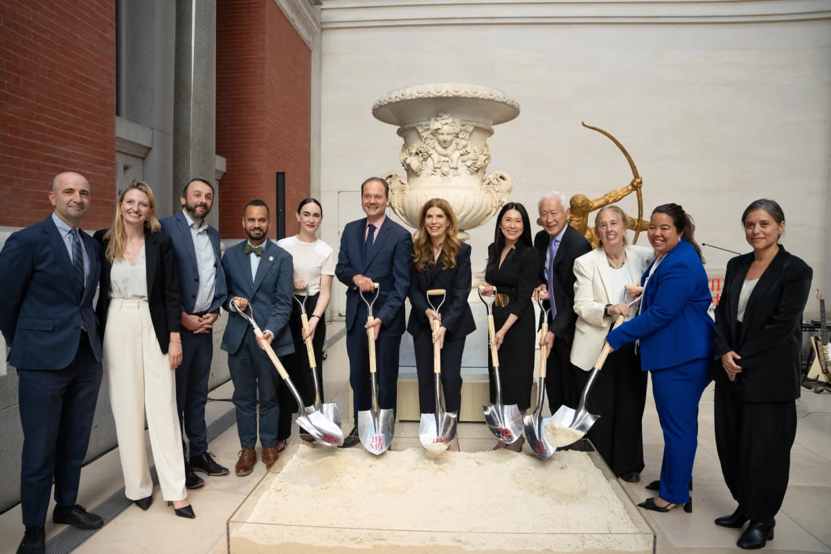 Dignitaries and architect standing with shovels in front of stone urn inside museum court