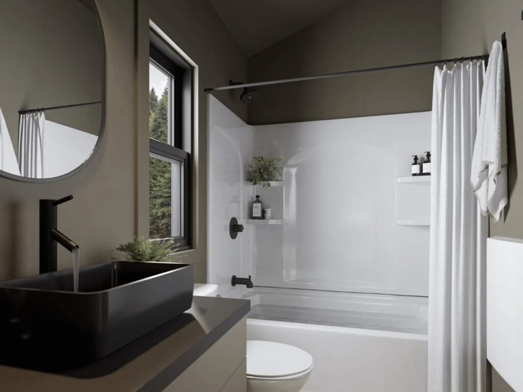 Modern bathroom in the A-Frame Bunkhouse featuring a black vessel sink on a vanity, a round mirror, and a full bathtub with shower surround behind a white curtain.