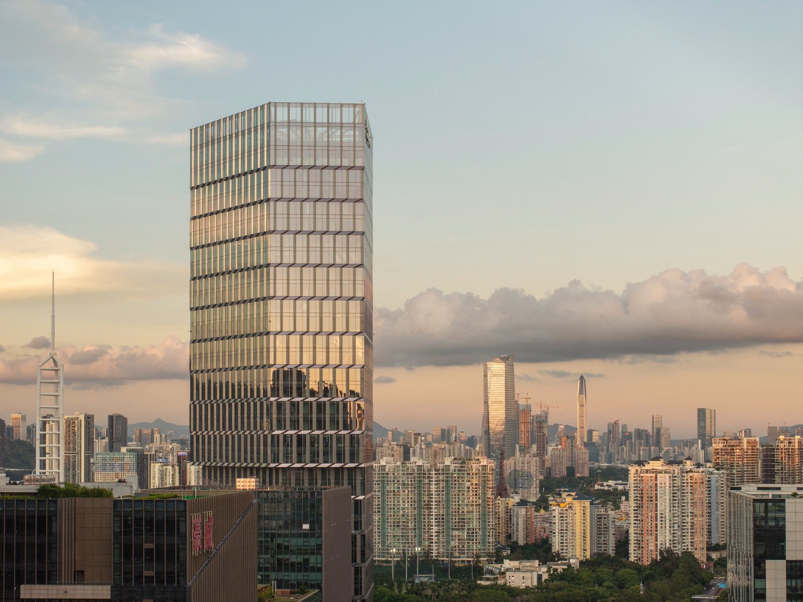 Kingdee HQ Tower in Nanshan Shenzhen standing 211 meters tall with its folded stainless steel and glass facade reflecting the sunset skyline.