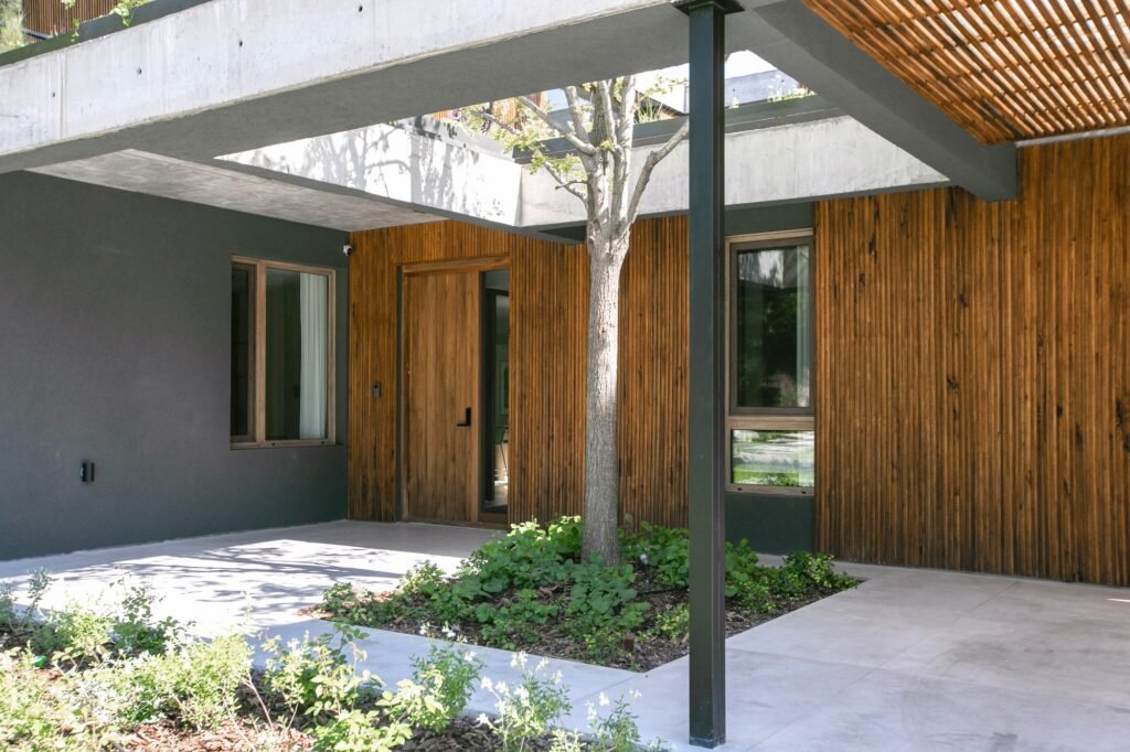 Covered main entrance porch of Casa MDL with a central tree growing through an open ceiling cutout surrounded by wood paneling.