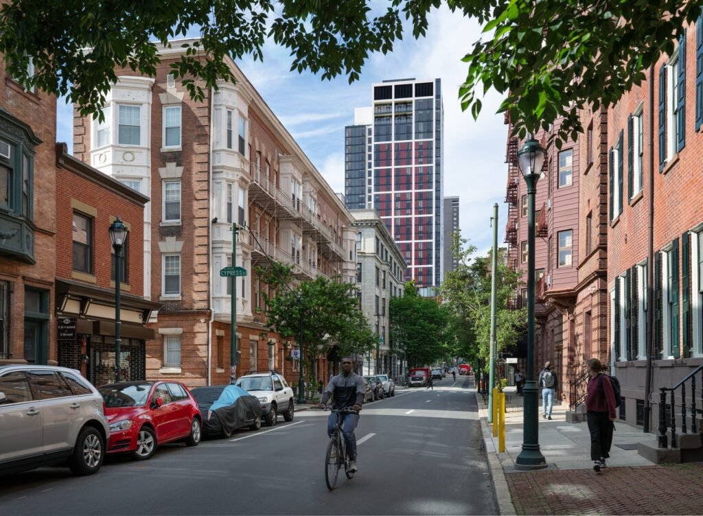 Street view looking down Cypress Street toward the modern 210 South 12th tower surrounded by historic brick townhouses in Philadelphia.