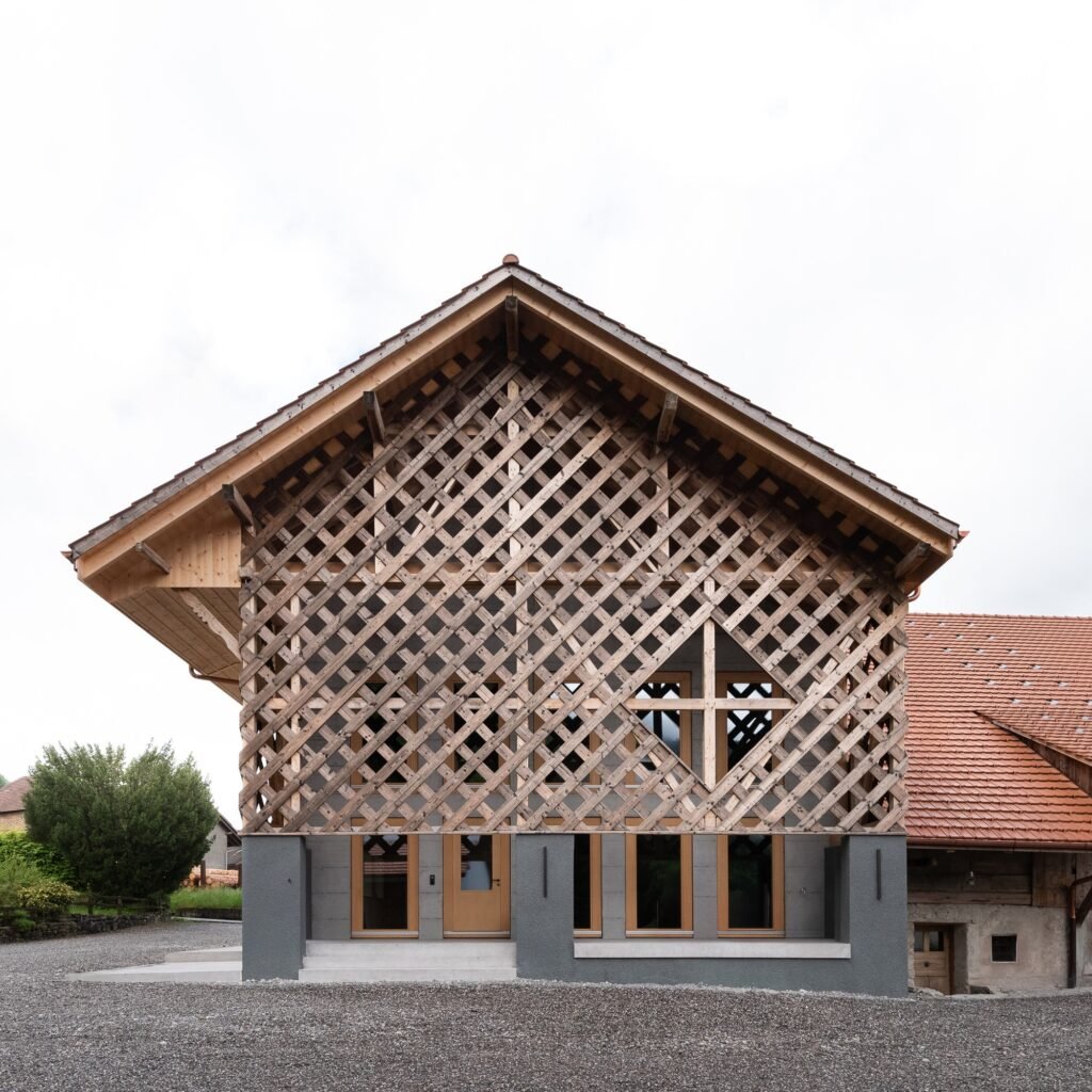 Front elevation of the agricultural wing featuring an intricate diamond-pattern wooden lattice screen atop dark grey concrete columns and modern glass entryways.