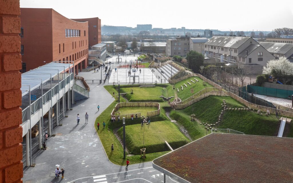 High-angle view of Campus Deleers outdoor school playground with terraced green landforms and sports courts.
