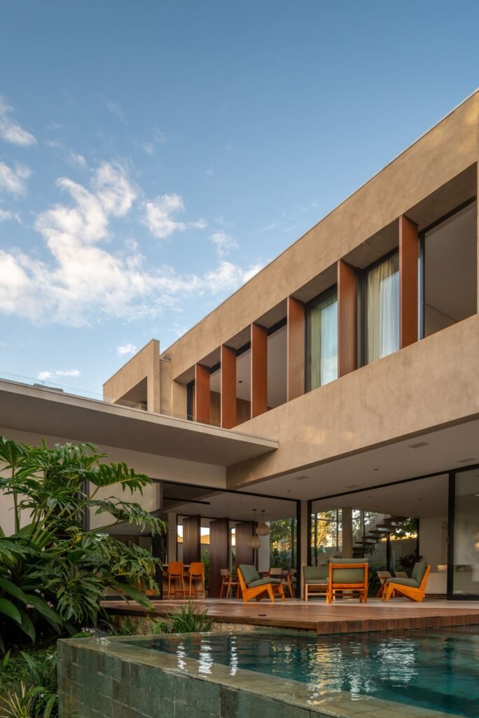 Casa Noor backyard terrace with outdoor swimming pool, wooden deck, open ground-floor living area, and vertical brise-soleil sunshades on the upper level.