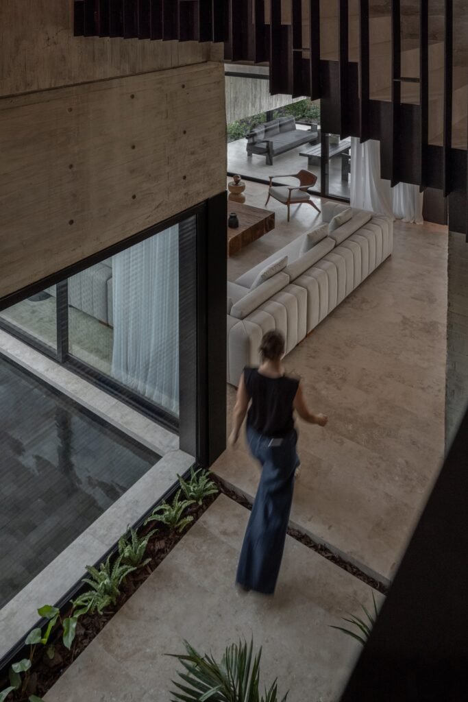 High-angle interior view of open hallway next to indoor water mirror feature and staircase with person walking.