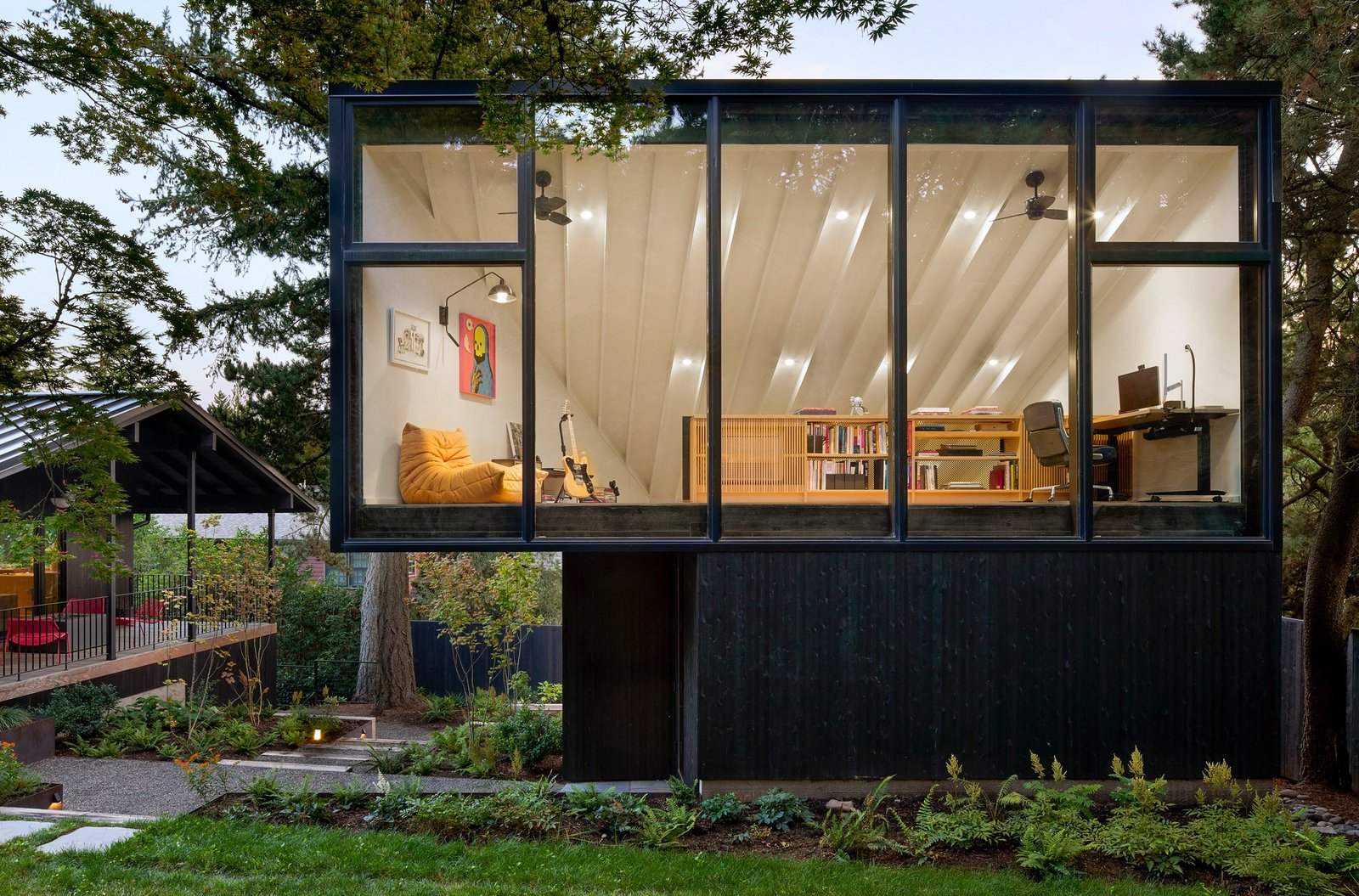 Exterior view of the detached two-story studio structure at 4015 House Studio in Portland featuring a large upper glass window and dark charred wood cladding.