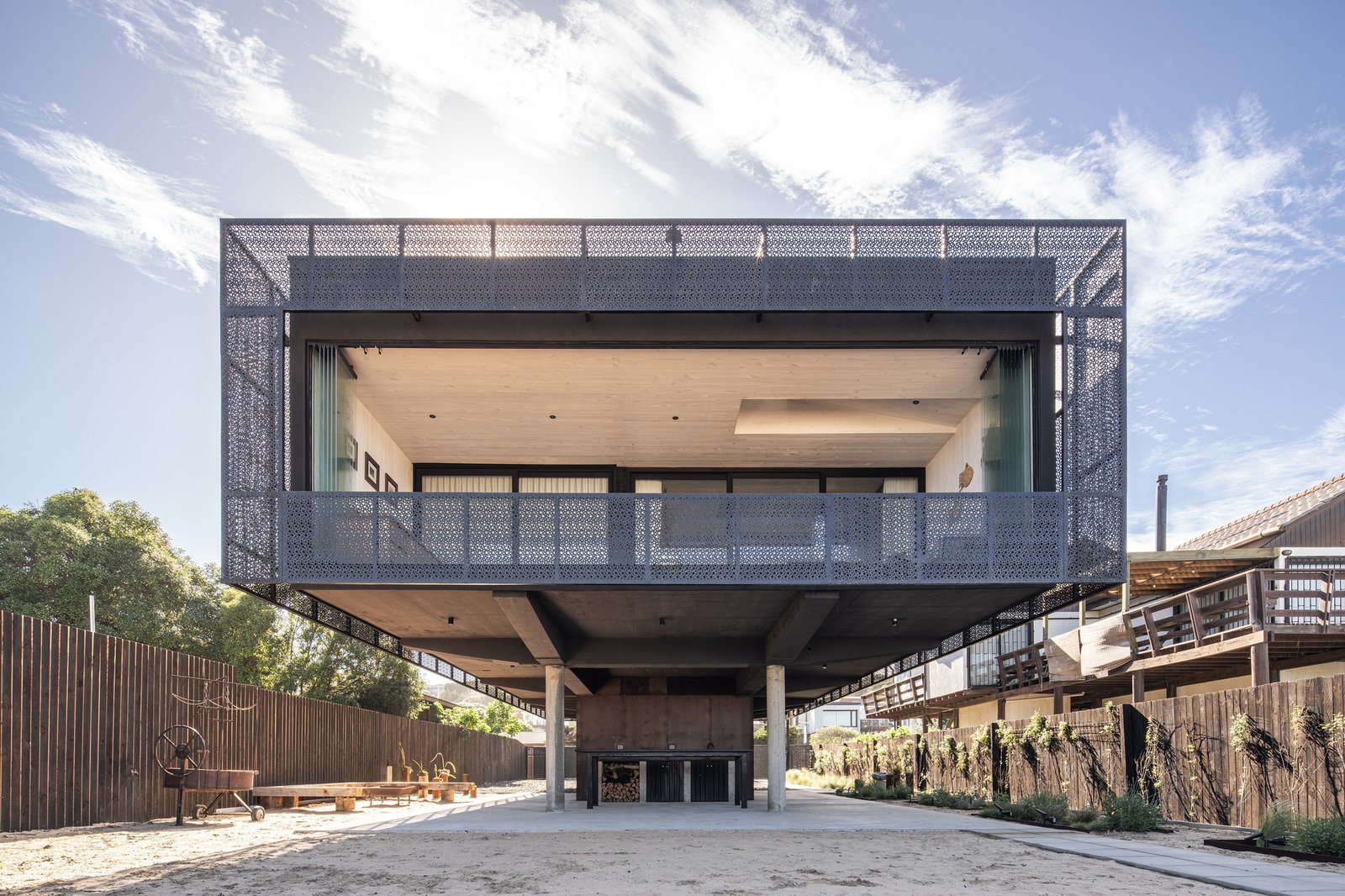 Elevated structure of Gandarillas House supported by concrete columns, showing the open ground floor level and perforated steel double skin facade.