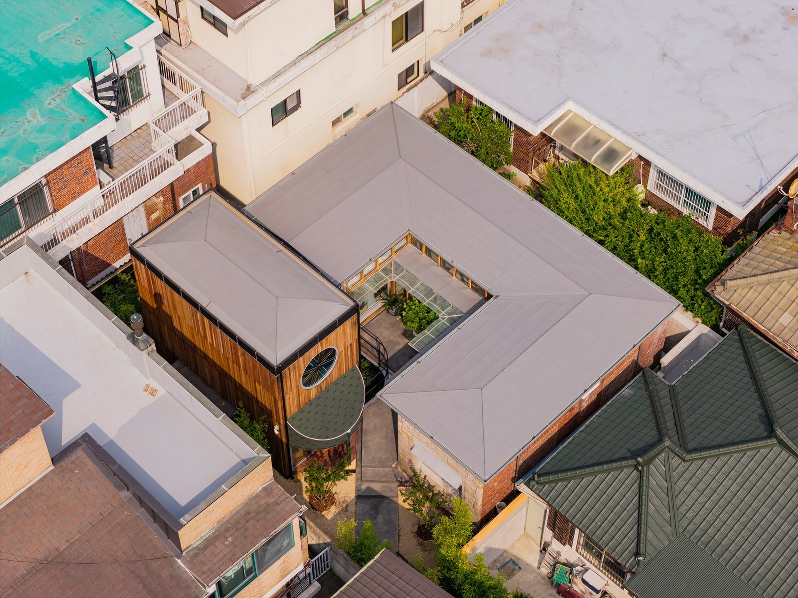 Aerial top-down view of Saekdong House in Yeonhui-dong showing its central courtyard, south extension wing, and surrounding dense urban context.