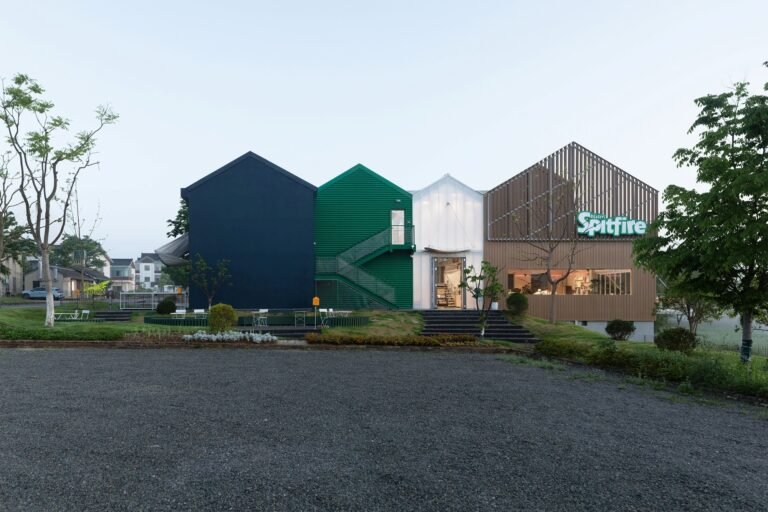 Exterior elevation of Spitfire Roastery by NOTA Architects showing four pitched-roof interconnected volumes with dark blue, green, white, and timber facades.