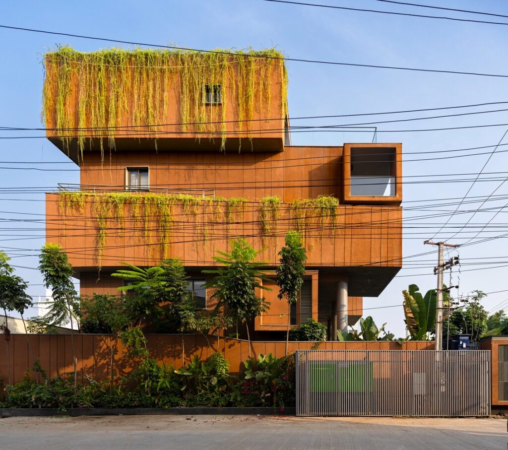 Side view of Erra Kotta Residence showing stacked terracotta volumes with cascading greenery and hanging vines.