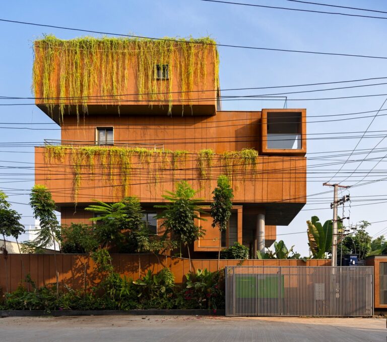 Side view of Erra Kotta Residence showing stacked terracotta volumes with cascading greenery and hanging vines.