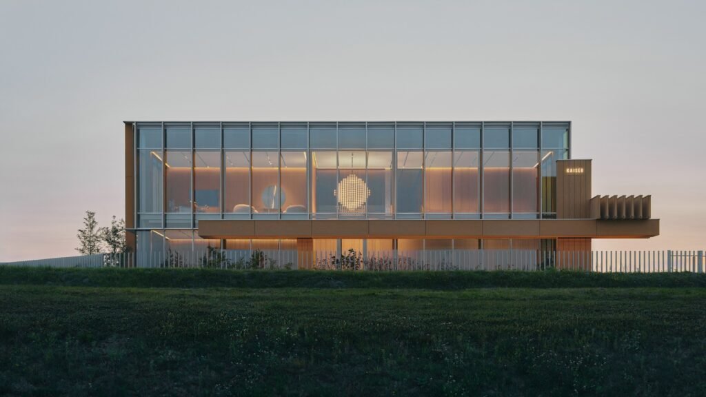 Exterior front elevation of OMNI KAISER Patisserie building by Pracownia at dusk showing an illuminated glass extension and modern facade.