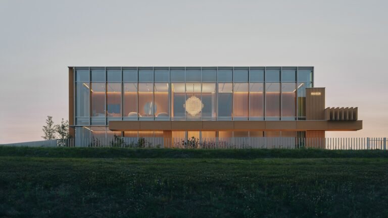 Exterior front elevation of OMNI KAISER Patisserie building by Pracownia at dusk showing an illuminated glass extension and modern facade.