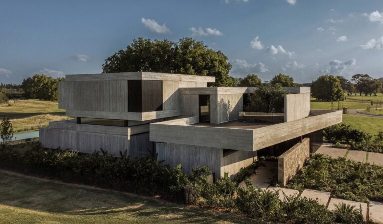 Modern concrete exterior showing layered volume levels and outdoor terraces at Grava House overlooking golf course landscape.