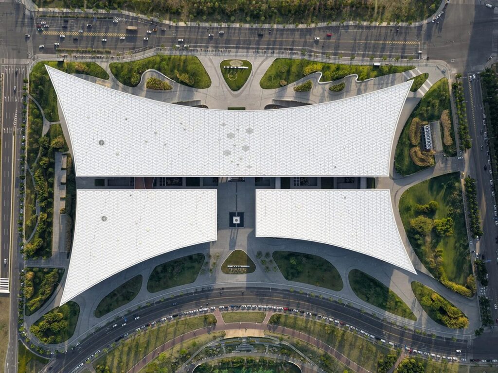 Top-down aerial view of Xi'an Public Library showing its open-book roof design and landscaped surrounding park plaza.